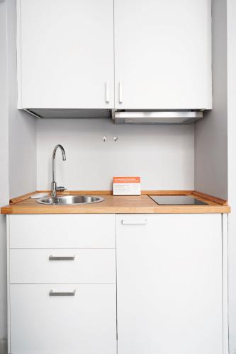 a kitchen with white cabinets and a sink at Numa Florence Rodo in Florence