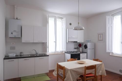 uma cozinha com armários brancos e uma mesa com cadeiras em Casa Alina- Art House em Foligno