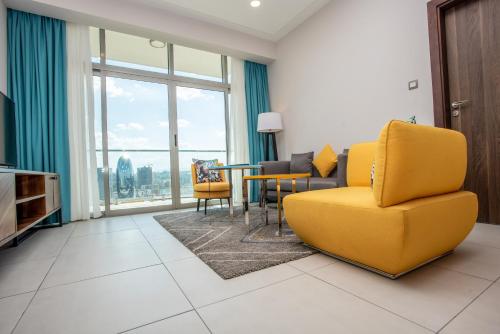 a living room with a yellow couch and a table and chairs at Skynest Residences by CityBlue, Nairobi Westlands in Nairobi