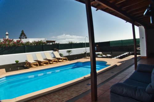 una piscina con tumbonas y un patio en Villa Raima, en Playa Blanca