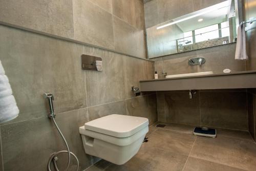 a bathroom with a toilet and a sink and a mirror at Skynest Residences by CityBlue, Nairobi Westlands in Nairobi