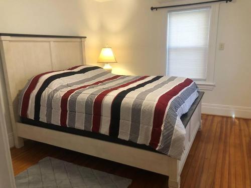 a bed with a striped comforter in a bedroom at Lovely old family home in Rochester