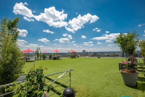 a large green field with red umbrellas on a roof at Skynest Residences by CityBlue, Nairobi Westlands in Nairobi