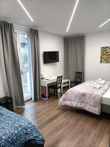 a bedroom with two beds and a desk and a window at Luxury B&B Iolanda in Catania