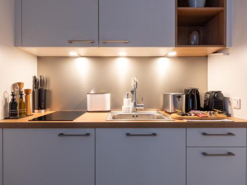 a kitchen with white cabinets and a sink at Limehome Linz Friedrichstraße in Linz