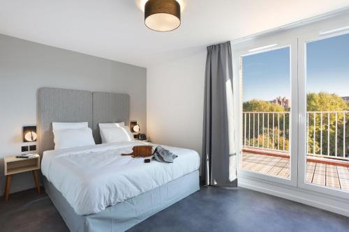a bedroom with a bed and a large window at Odalys City Toulouse Centre Compans Caffarelli in Toulouse