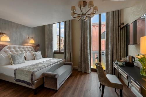a hotel room with a bed and a desk and a window at Palazzo Veneziano - Venice Collection in Venice