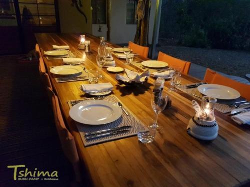 a long wooden table with plates and glasses on it at Tshima Bush Camp in Komane