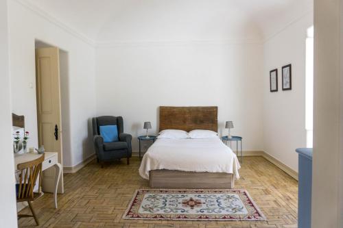 a white bedroom with a bed and a chair at Torre da Giesteira in São Brissos