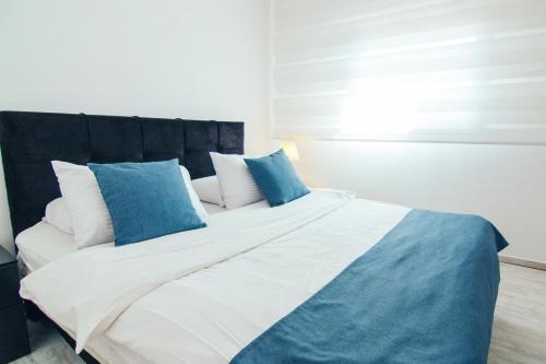 a bedroom with a large bed with blue and white pillows at Almog Haifa Israel Apartments מגדלי חוף הכרמל in Haifa