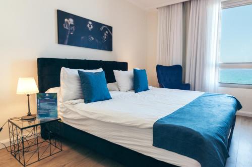 a bedroom with a large bed with blue pillows at Almog Haifa Israel Apartments מגדלי חוף הכרמל in Haifa