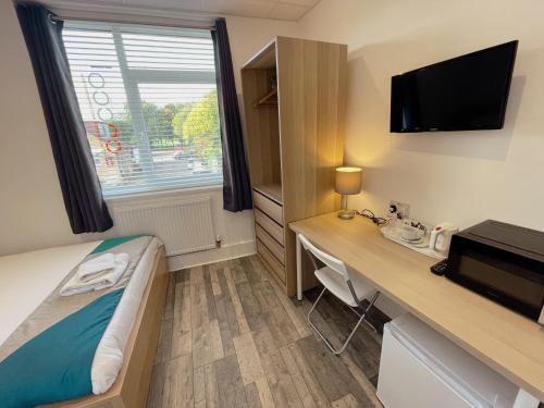 a room with a bed and a desk and a television at CACCO - Contractor Accommodation in Corby