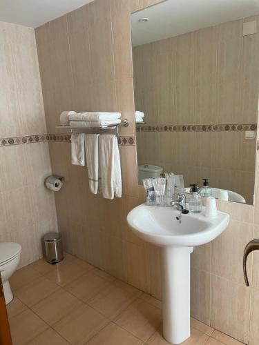 a bathroom with a sink and a toilet and a mirror at Hostal María in Elche