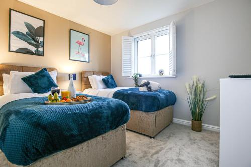 a bedroom with two beds with blue comforters at Luxury House - Sleeps 12 - Smart TVs, Fast Wifi, Garden and Free Parking by Yoko Property in Kempston