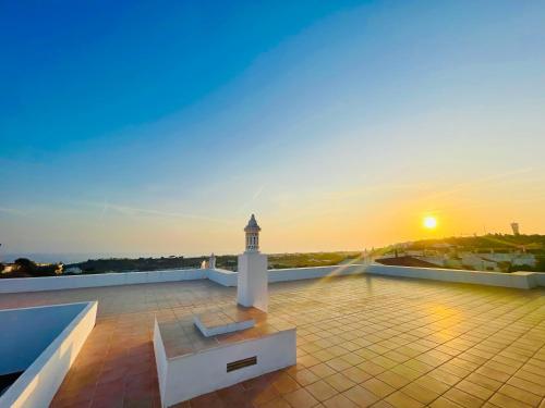 a sunset on the roof of a building with a lighthouse at Ocean View Skyline Apartment ‚Hakuna Matata‘ in Albufeira