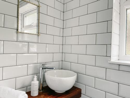 a white tiled bathroom with a sink and a mirror at Old Pier Cottage Tarbert in Tarbert