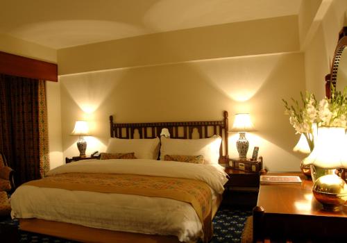a bedroom with a large bed and two lamps at Faisalabad Serena Hotel in Faisalabad