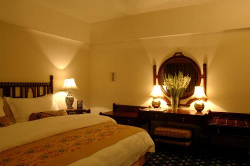 a bedroom with a bed and a table with two lamps at Faisalabad Serena Hotel in Faisalabad