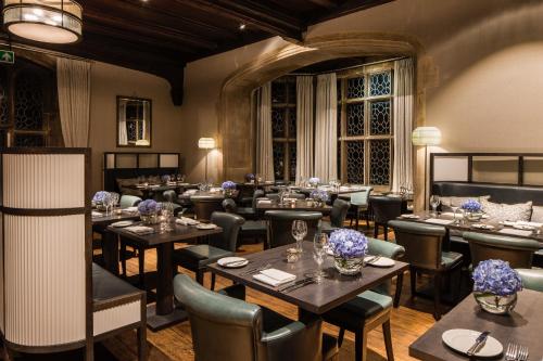 a restaurant with tables and chairs in a room at Eastwell Manor, Champneys Hotel & Spa in Ashford
