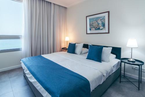 a bedroom with a large bed with blue pillows at Almog Haifa Israel Apartments מגדלי חוף הכרמל in Haifa