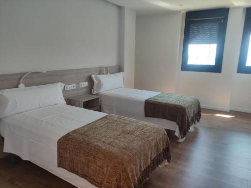 a hotel room with two beds and a window at Alojamientos Central in Porriño