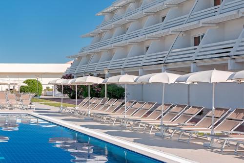a hotel with chairs and umbrellas next to a swimming pool at Hotel Olympia in Vodice