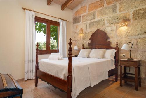 a bedroom with a bed and a stone wall at Alcudiola in Santa Margalida