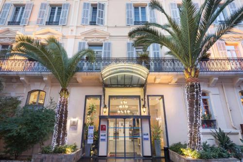 a building with two palm trees in front of it at Best Western Hotel Lakmi Nice in Nice