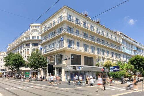 un gran edificio en una calle de la ciudad con gente cruzando la calle en Best Western Hotel Lakmi Nice en Niza