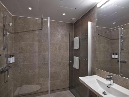 La salle de bains est pourvue d'une douche et d'un lavabo. dans l'établissement Scandic Luleå, à Luleå