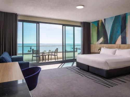 a hotel room with a bed and a view of the ocean at Novotel Geelong in Geelong