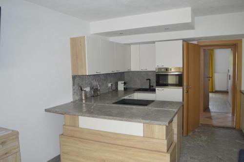 a kitchen with white cabinets and a gray counter top at Ferienwohnungen Restaurant Pizzeria Langreiter in Embach