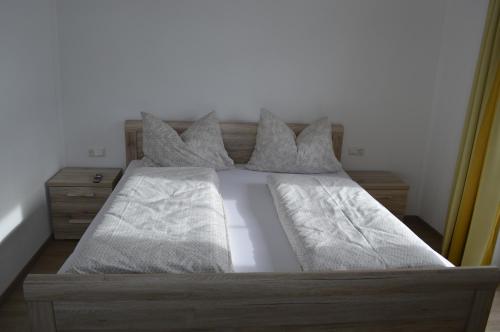 a bed with white sheets and pillows on it at Ferienwohnungen Restaurant Pizzeria Langreiter in Embach