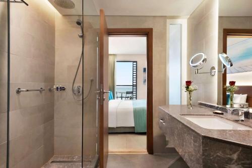 a bathroom with a shower and a sink and a mirror at Wyndham Garden Ajman Corniche in Ajman 