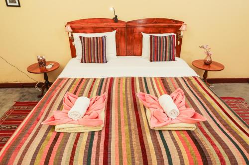 a bedroom with a bed with pink towels and two tables at The Colonial Guest House in São Filipe