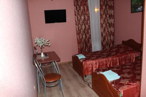a small room with a bed and a table with a chair at Hotel Dinastiya in Nizhny Novgorod
