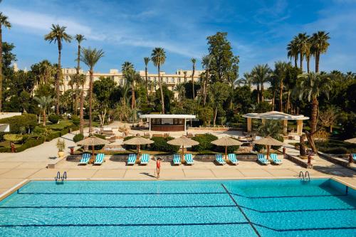 a pool at a resort with chairs and umbrellas at Sofitel Winter Palace Luxor in Luxor