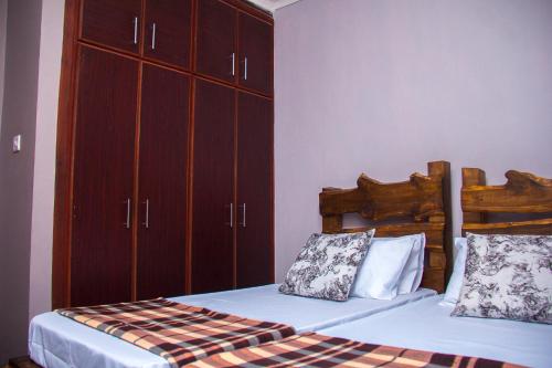 a bedroom with two beds and a large cabinet at MINA CHAI HOUSE BNB in Arusha