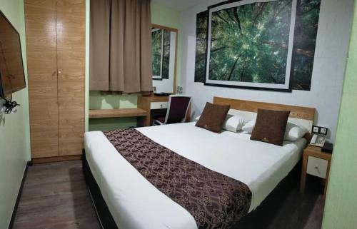 a hotel room with a large bed and a desk at Golden Nasmir Hotel Sdn Bhd in Bukit Mertajam
