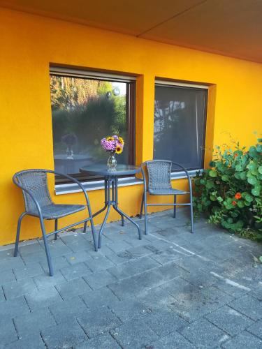 une table et des chaises devant un mur jaune dans l'établissement Ferienwohnung Heijungs, à Herdwangen-Schönach
