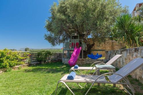 a yard with two chairs and a tree and a swing at Margarita's Villas in Chania Town