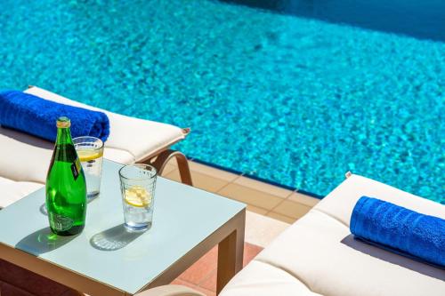 a bottle and glasses on a table next to a swimming pool at Margarita's Villas in Chania Town