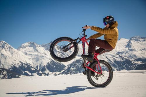 a man doing a trick on a bike in the snow at Catrina Hotel in Disentis
