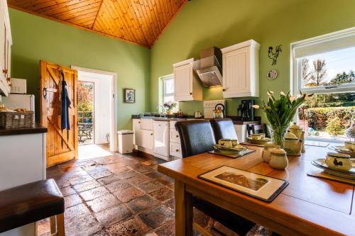 a kitchen with green walls and a wooden table at Brookhall Cottages in Lisburn