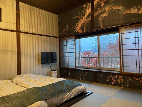 a bedroom with a bed and a tv and windows at 元町の宿　雪月花 in Hakodate
