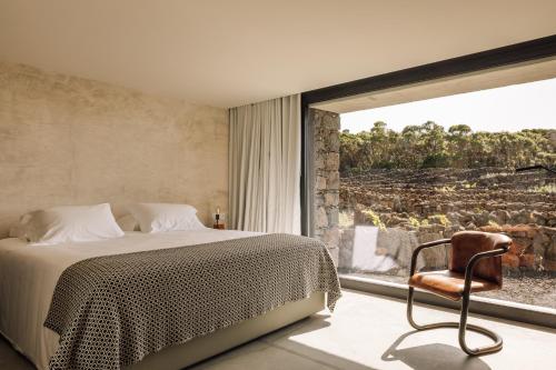 1 dormitorio con 1 cama, 1 silla y 1 ventana en Azores Wine Company, en Cais do Mourato