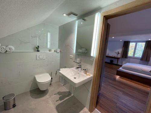 uma casa de banho branca com um WC e um lavatório em Hotel Reich am Ebnisee em Kaisersbach