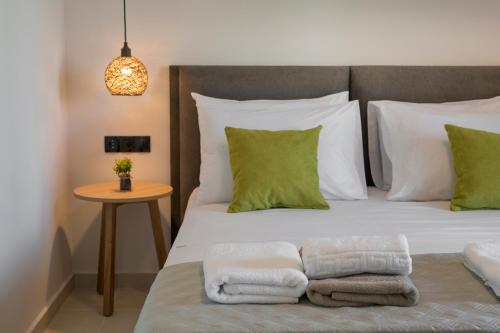 a bed with green and white pillows and a table at Aegean Breeze Luxury Apartments next to the sea in Maleme