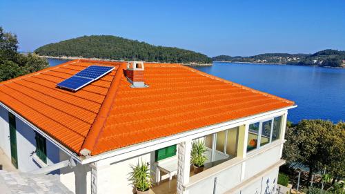 ein Haus mit einem orangenen Dach mit einer Solaranlage darauf in der Unterkunft Holiday Home Katica in Vela Luka