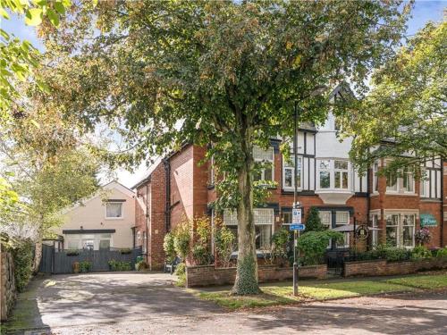 a house with a tree in front of a street at Acorn Lodge Harrogate in Harrogate
